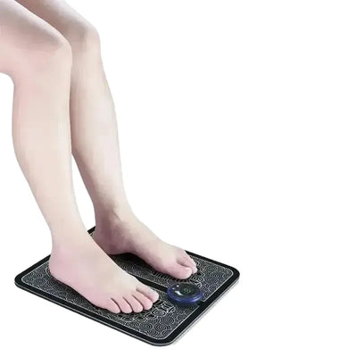 Feet on a rechargeable EMS foot massager pad with control dial, showing features like acupoint capture and USB charging.